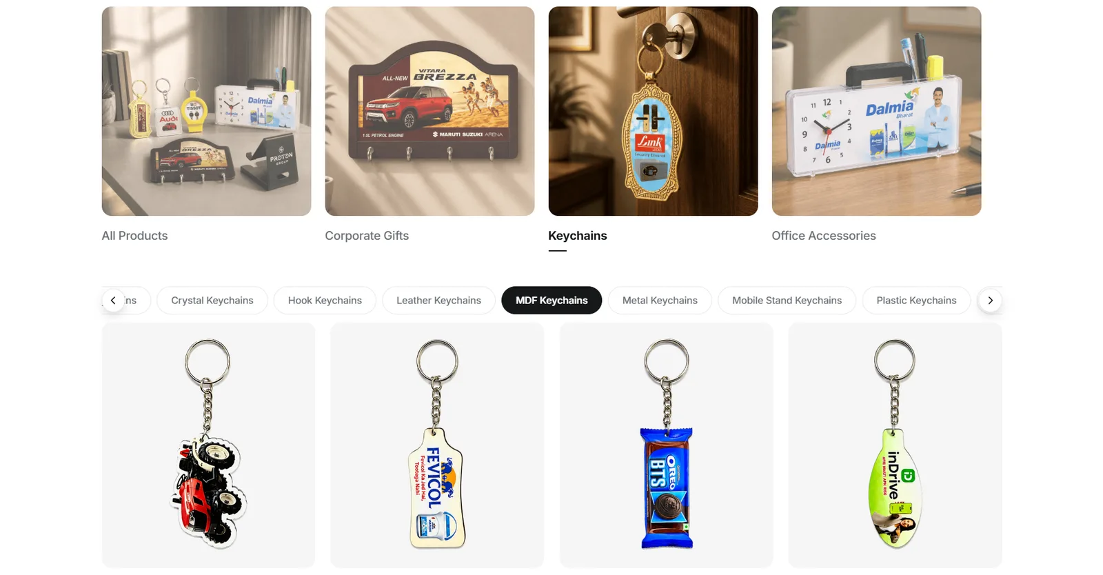 The keychain grid under a scrolling strip of material chips — crystal, hook, leather, MDF, metal, mobile stand, plastic — with four branded designs shown and no price on any card.